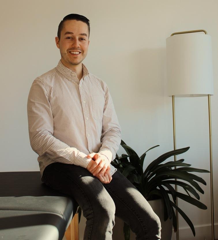A man standing indoors beside a plant